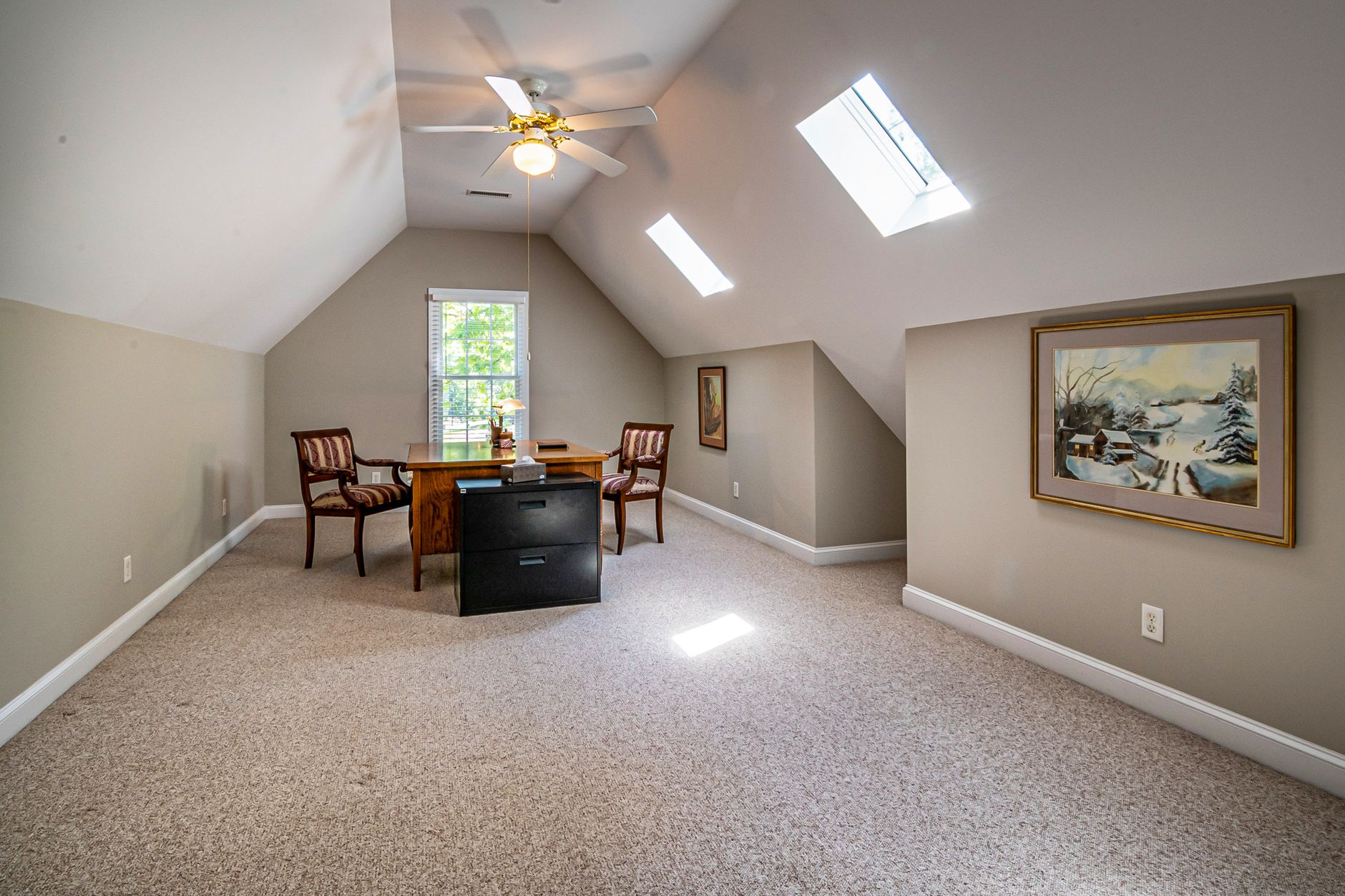 A finished room over a garage doing the job it usually does: an office, because the roof line and the window rule out a bedroom
