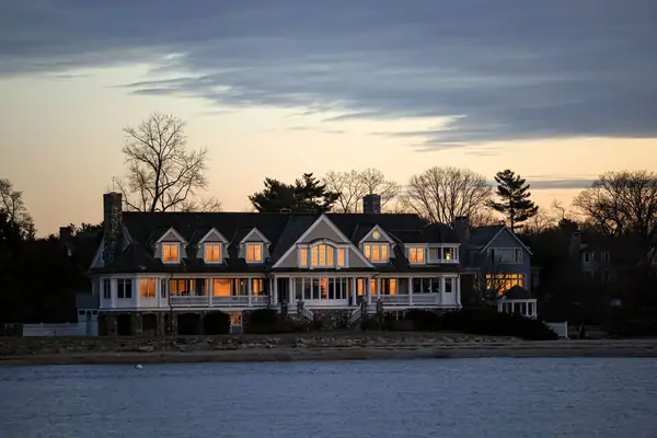 A waterfront house on Long Island Sound at dusk, with the trees bare