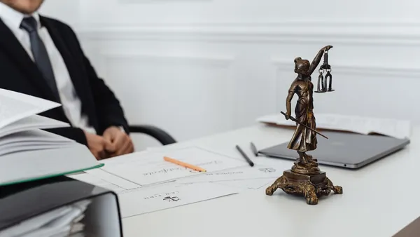 A small brass scales-of-justice figure on a desk - commission rebate