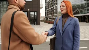 Two people shaking hands on a city street outside a building