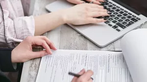Reviewing license verification paperwork alongside a laptop