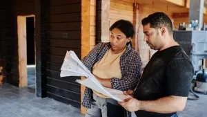 A contractor and homeowner reviewing renovation plans on site in New York