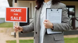 A real estate agent holding a signed purchase and sale agreement outside a home for sale