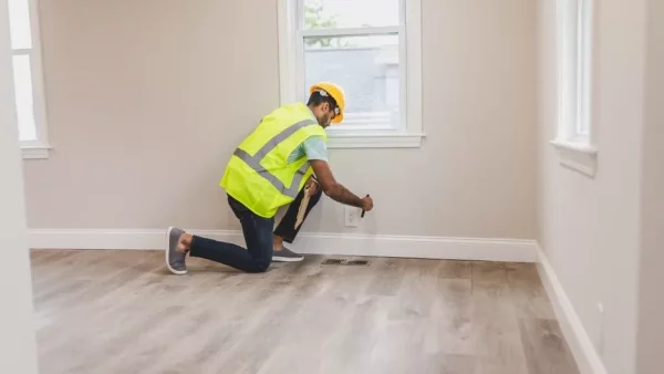A home inspector checking an electrical outlet during a walkthrough