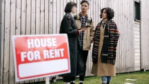 Prospective tenants looking at a house for rent sign before a move-in inspection