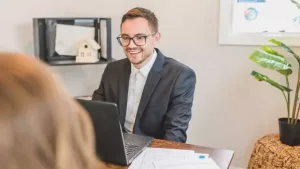 A real estate agent meeting with a client at his office desk