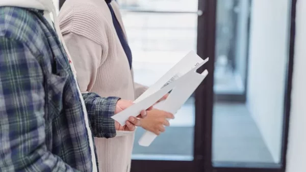 nys disclosure form for landlord and tenant - Two tenants holding lease paperwork while touring an apartment