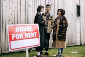 Prospective tenants looking at a house for rent sign before a move-in inspection - normal wear and tear