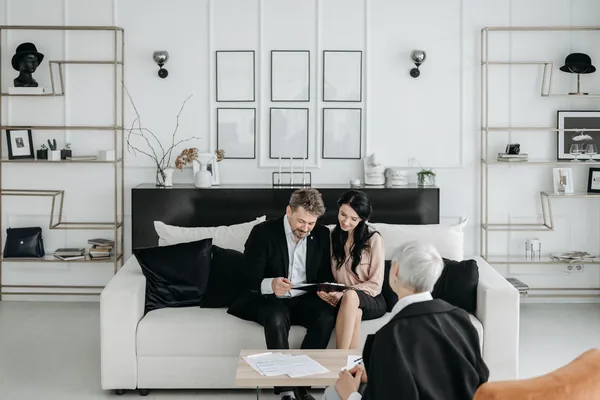 A parent and adult child reviewing mortgage co-signer paperwork with a lender