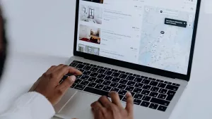 Hands typing on a laptop showing apartment listings and a map