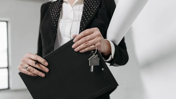 A real estate agent holding a folder with a set of house keys