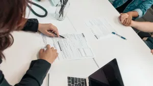 People reviewing real estate paperwork and a laptop at a table