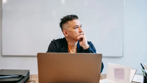 A person pausing to think while working at a laptop