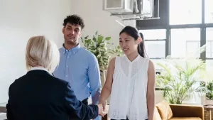 A real estate agent talking with a young couple in a bright room
